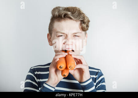 Boy Eating Three Large Carrots Stock Photo