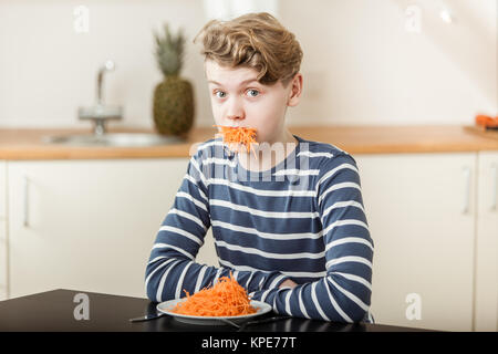 Boy at Table with Mouthful of Shredded Carrots Stock Photo