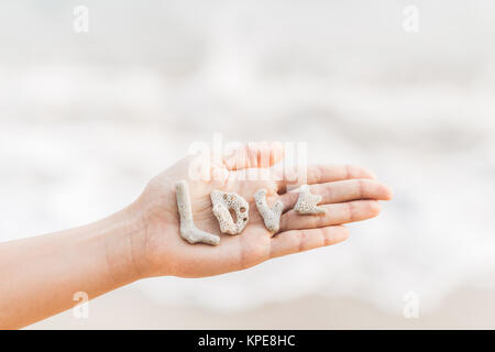 Word love made of shells on woman hand Stock Photo