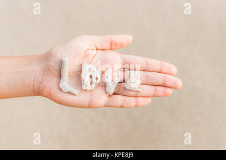 Word love made of shells on woman hand Stock Photo