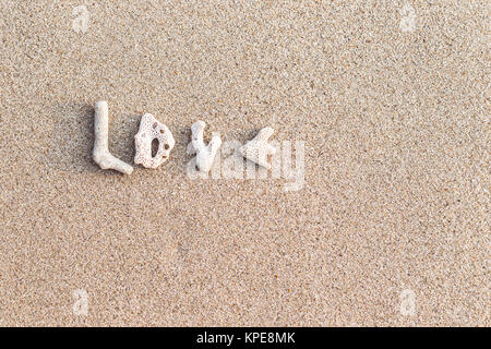 Love inscription made of shells on white sand Stock Photo