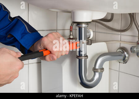 Male Plumber Repairing Sink In Bathroom Stock Photo