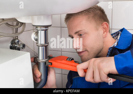 Male Plumber Fixing Sink In Kitchen Stock Photo