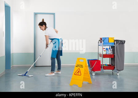 Female Janitor Mopping Corridor Stock Photo