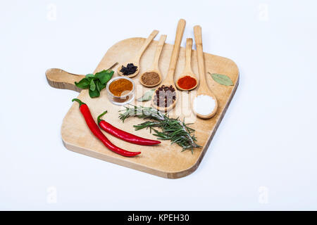 Colorful spices and spoons on cutting board Stock Photo