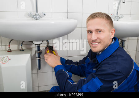 Plumber Fixing Sink In Bathroom Stock Photo
