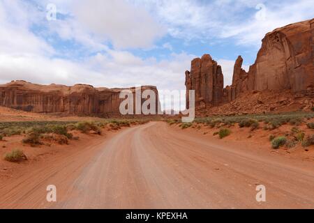 Red Desert Valley Road - A unpaved dirt road winding through red sandstone desert valley in the famous Monument Valley, Utah & Arizona, USA. Stock Photo