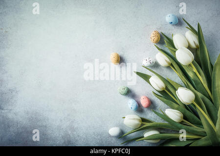 Spring and Easter background. White tulips with colorful quail eggs. Holiday concept with copy space. Stock Photo