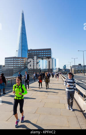 London, UK. Early morning commuters walk and jog north across London Bridge. Stock Photo