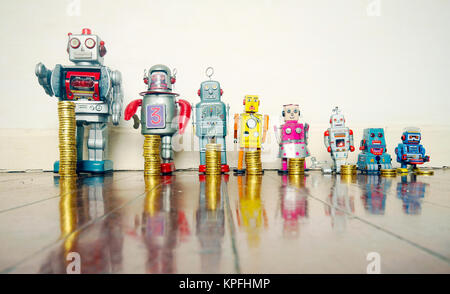 A line of retro toys with staks of gold coines on a wooden floor concept equality Stock Photo