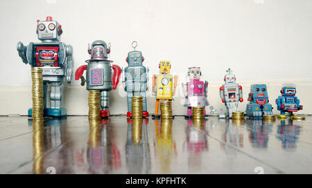 A line of retro toys with staks of gold coines on a wooden floor concept Stock Photo