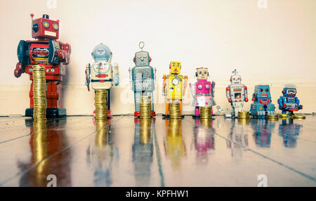 A line of retro toys with staks of gold coines on a wooden floor concept equality Stock Photo