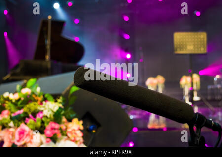 close up on a microphone during recording session with a singer piano in the background music studio Stock Photo
