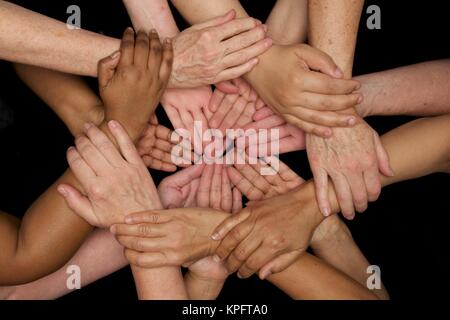 hands of many colors unite in harmonious diversity  and heart felt team work Stock Photo