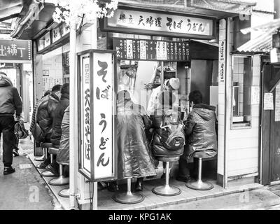 Tokyo, Japan - February 19, 2014: A group of men eating in a small izakaya (bar) in a little alley of Shinjuku district, Tokyo. Stock Photo