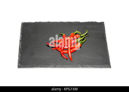 Red chilli peppers laid on a slate platter isolated on a white background Stock Photo