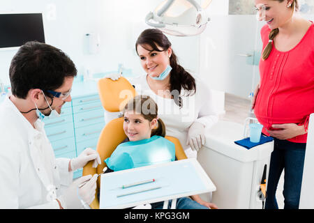 dentist treats child with mother in his practice Stock Photo