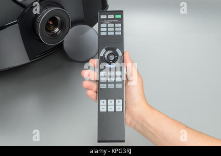 Huge black home cinema projector, hand presenting the remote Stock Photo