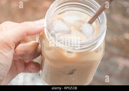 Hand on glass of iced milk coffee with vintage filter effect Stock Photo
