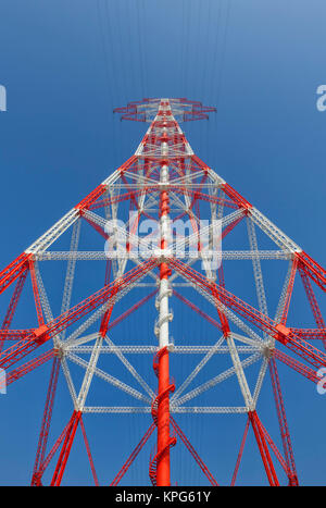 Red and white electricity pylon against blue sky, low angle view Stock Photo
