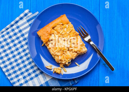 Apple cake piece on blue plate with fork and checkered napkin on blue wooden table, top view Stock Photo