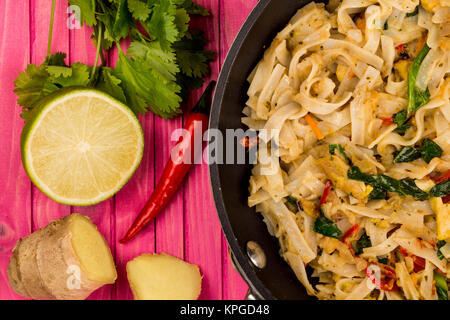 Thai Style Chicken Pad Thai With Noodles On A Pink Wooden Background Stock Photo