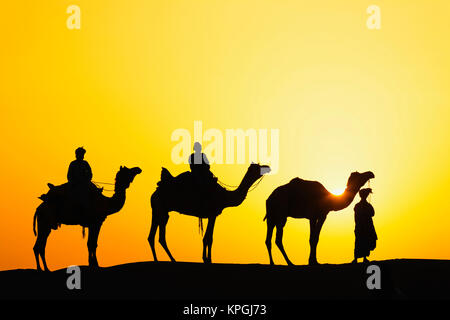 Camels and camel driver silhouetted at sunset, Thar Desert, Udaipur, India. Stock Photo