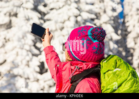 Close up of caucasian woman in colorful outfit taking a break from backcountry skiing to take a picture record the beautiful winter scenery Stock Photo