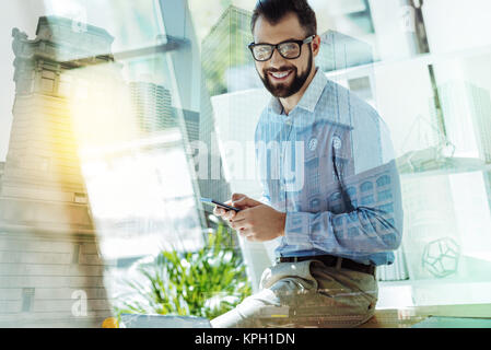 Pleasant joyful man using the smartphone and looking straight. Stock Photo