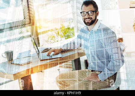 Bearded handsome man smiling and using the laptop. Stock Photo