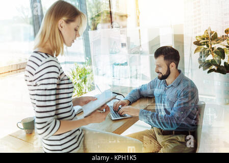 Young nice-looking workers communicating and helping each other. Stock Photo