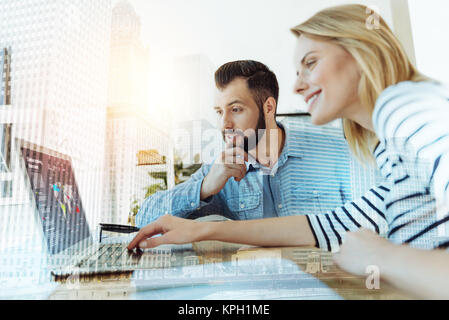Couple of young perspective workers using laptop and looking like thoughtfully. Stock Photo