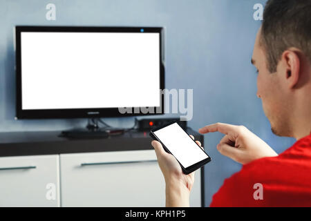 Relaxed man with smartphone connected to a tv. Blank screen white screen. The form for information. TV screen without information and content. Using a Stock Photo