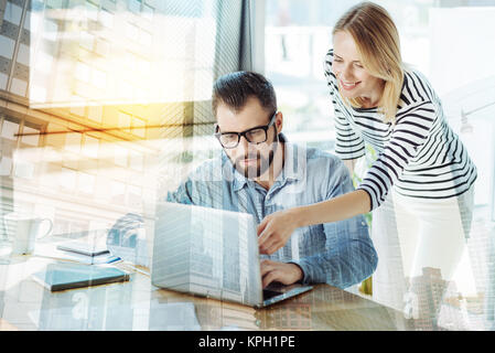 Stylish nice-looking colleagues working and using the laptop. Stock Photo