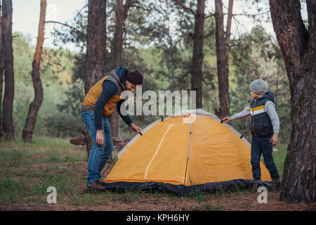 father and son putting up tent Stock Photo