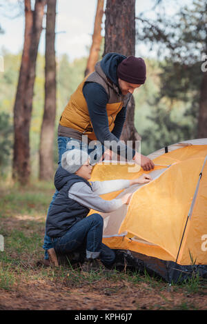 father and son putting up tent Stock Photo