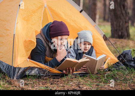 father and son reading books in tent Stock Photo