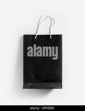 Mockup of black blank paper shopping bag with rope handles on white paper background. Flat lay. Stock Photo