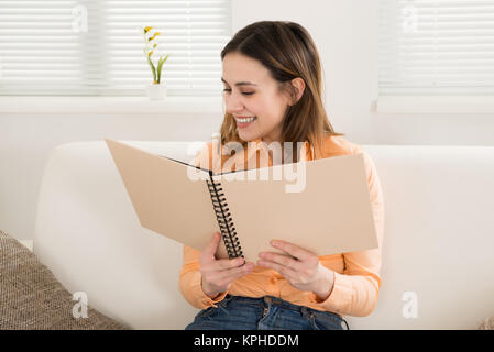 Woman Smiling While Looking At Photo Album Stock Photo
