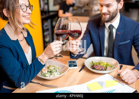 Business couple having a conversation during the dinner clinking glasses at the restaurant Stock Photo