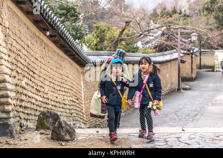 Nara, Japan - February 26, 2014 - A couple of girls walking to the school by the streets of Nara, Japan Stock Photo