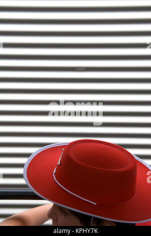 cropped view of young boy wearing a red cowboy hat with a metal shutter in background Stock Photo