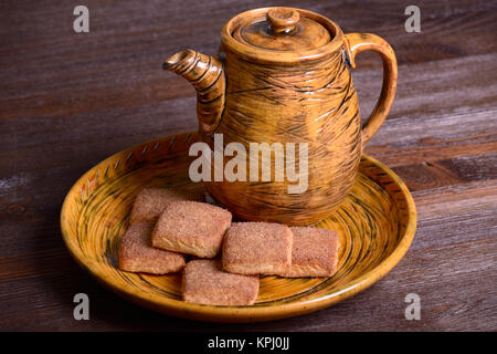 Cookies with cinnamon on a platter and teapot on a wooden board Stock Photo