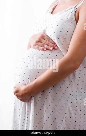 Pregnant Woman with nightgown standing near  window at home Stock Photo