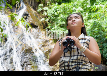 Girl using binoculars in forest Stock Photo