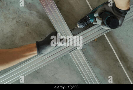 Man assembles profile metal frame for plasterboard ceilings Stock Photo