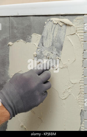 Installation of mosaic tiles. The worker puts adhesive on the base Stock Photo