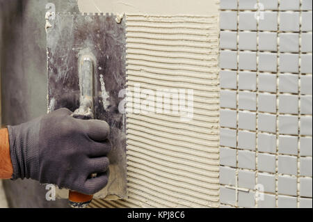 Installation of mosaic tiles. The worker puts adhesive on the base Stock Photo