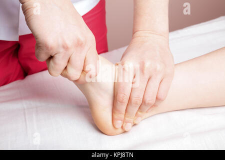 Elementary age girl's foot joint being manipulated by an osteopath - an alternative medicine treatment Stock Photo