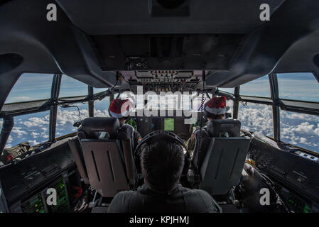 U.S. Air Force pilots wearing Santa hats fly their C-130J Super Hercules cargo aircraft to airdrop supplies to remote parts of Micronesia during the 66th Operation Christmas Drop December 15, 2017 in Yigo, Guam. Every December American and Australian C-130 Hercules crews airlift food, supplies, tools and toys to islanders throughout Micronesia. Stock Photo